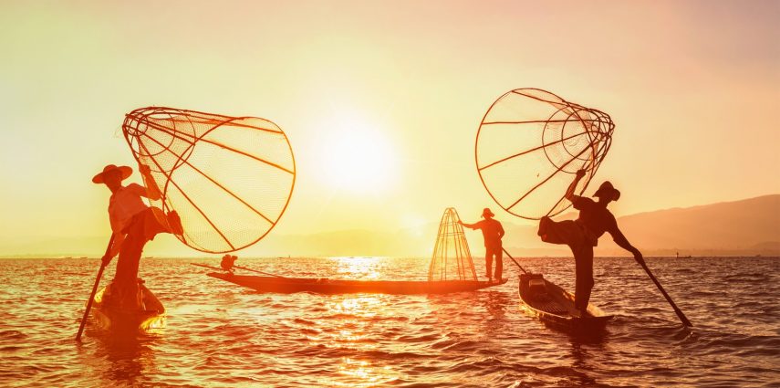 Myanmar travel attraction landmark - three traditional Burmese fishermen at Inle lake, Myanmar famous for their distinctive one legged rowing style